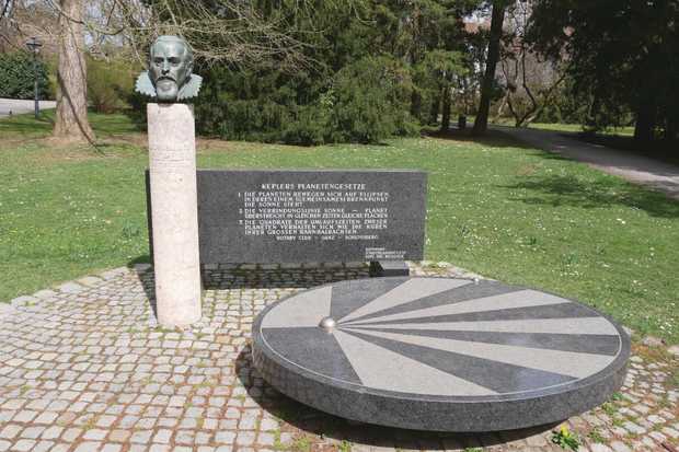 Eine Stein-Büste von Johannes Kepler vor einer Marmortafel mit Keplers Gesetzen und einer runden Marmorplatte.