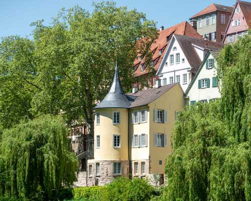 La tour Hölderlin sur le Tübingen Neckar: Un bâtiment jaune avec une tour ronde et un toit pointu.