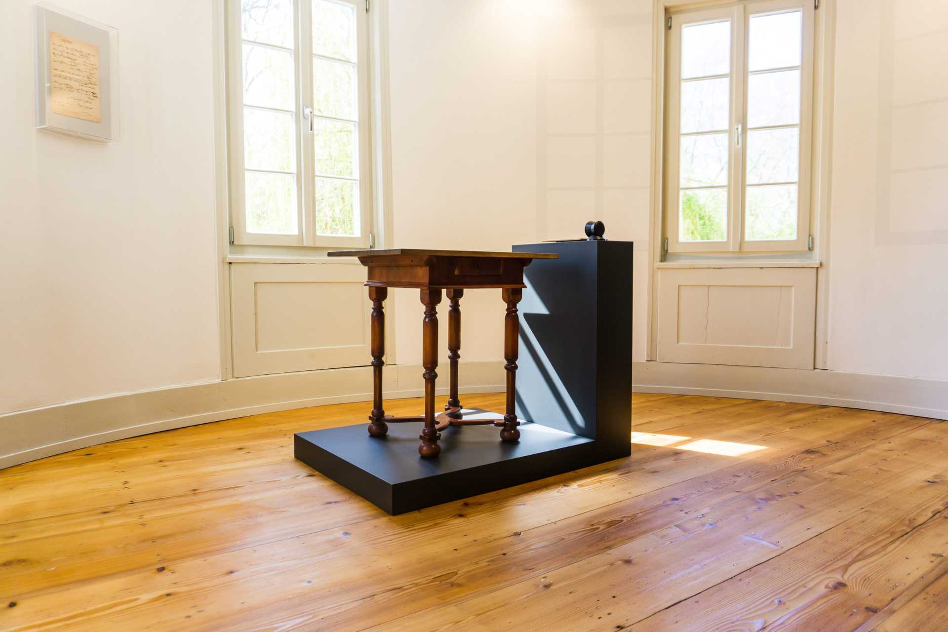 Hölderlins Turmzimmer mit Schreibtisch in der Mitte und Manuskript an der Wand